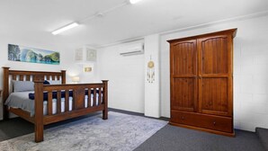 A bedroom with a wooden bed, a large wardrobe, a wall clock, and a painting. - 3 Bedrooms Vista Point Sanctuary (Burleigh Heads)