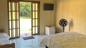 Une chambre avec deux lits, une télévision, un ventilateur et un petit réfrigérateur.