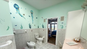 Une salle de bain équipée de toilettes, d’un bidet et d’un lavabo.