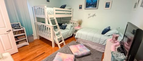 Un dormitorio infantil con literas, un escritorio y una estantería.