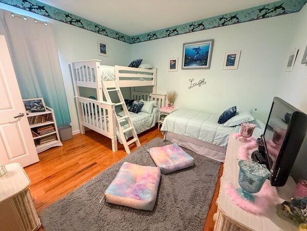 Ein Kinderzimmer mit Etagenbetten, einem Schreibtisch und einem Bücherregal.