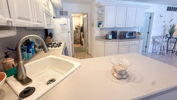 A modern kitchen with white cabinetry, a stainless steel sink, and a microwave. - Beach Front. Water Views. Inground Pool. (Cape May)