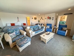 Ein Wohnzimmer mit einer Sofagarnitur, einem Couchtisch und einem blauen Sessel.
