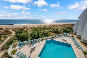 Ein Swimmingpool mit Liegestühlen und Blick auf den Strand.