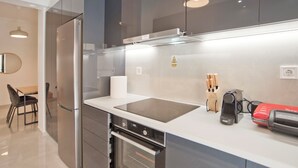 Une cuisine moderne dotée d’appareils électroménagers en acier inoxydable, d’un four encastré et d’un plan de travail sur lequel se trouve un grille-pain rouge.