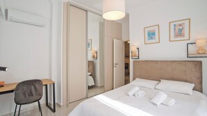 Une chambre d’hôtel avec un lit, un bureau, une chaise et une armoire.