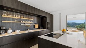 Eine moderne Küche mit dunklen Schränken, einer weißen Arbeitsplatte und einem eingebauten Backofen.