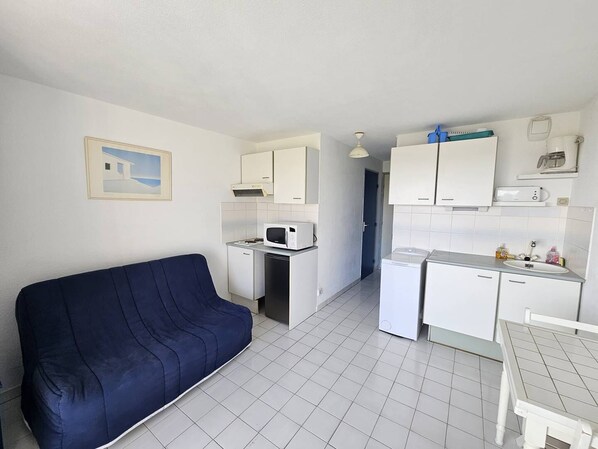 A compact living space with a kitchenette, a microwave, a refrigerator, a sink, and a small dining table. - CAP D'AGDE - Plage Richelieu / Réf 278 (CAP D'AGDE)