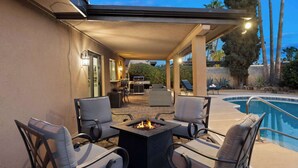 Un espace extérieur aménagé avec une terrasse, une piscine, un foyer et du mobilier de jardin.