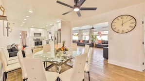 A spacious living area with a glass dining table, white chairs, a ceiling fan, and a large wall clock. - Versace Vibes Retreat, Pool Sauna Near Hard Rock (Hollywood)