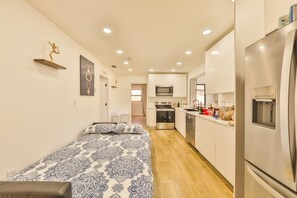 Ein kompaktes Apartment mit einer Küchenzeile, einem Bett mit gemusterten Textilien und einem kleinen Essbereich.