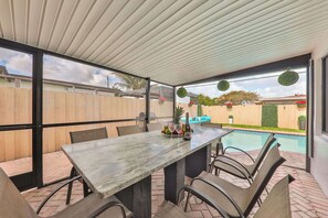 Eine Außenpatio mit Tisch und Stühlen, einem Pool und einem Holzzaun im Hintergrund.