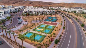 A residential area with modern houses, a curved road, and multiple tennis courts.