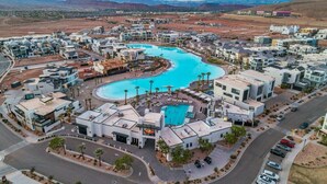 A residential area with modern architecture, a central swimming pool, and a mountainous backdrop.