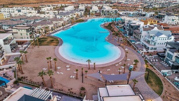 A resort with a large pool, palm trees, and modern buildings.