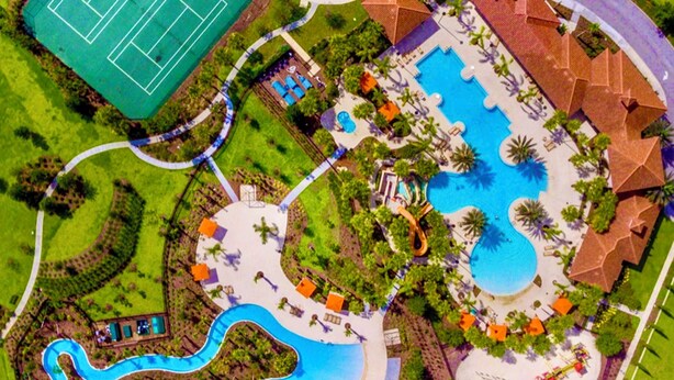 Oversigtsbillede af en feriepark med et stort swimmingpool, en tennisbane og en snoet vandrutsjebane.