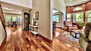 Un salon spacieux doté de planchers en bois franc, d’une cheminée et de grandes fenêtres.