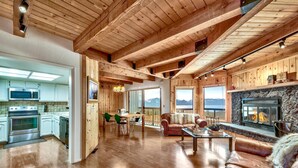 Un vaste espace de vie doté d’une cheminée, de poutres apparentes en bois et offrant une vue sur les montagnes.