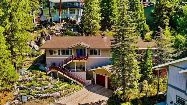A two-story house with a balcony, surrounded by dense trees and rocky terrain. - LX35  The Wolf Round Hill Retreat in the heart of Lake Tahoe (Zephyr Cove)