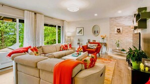 A modern living room with a sofa, armchair, and coffee table. There is a fireplace, a mirror, and a window with curtains. - LX35  The Wolf Round Hill Retreat in the heart of Lake Tahoe (Zephyr Cove)
