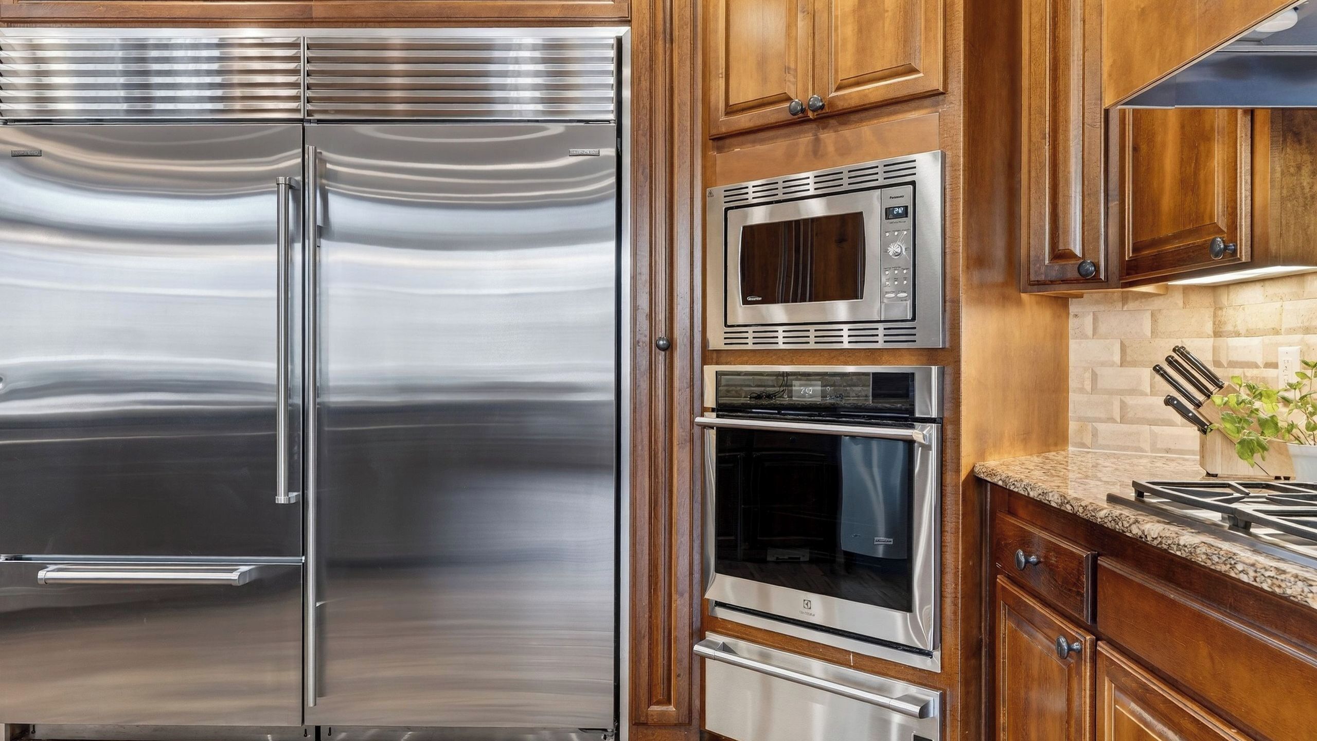 Una cocina con electrodomésticos de acero inoxidable, armarios de madera y encimera de granito.