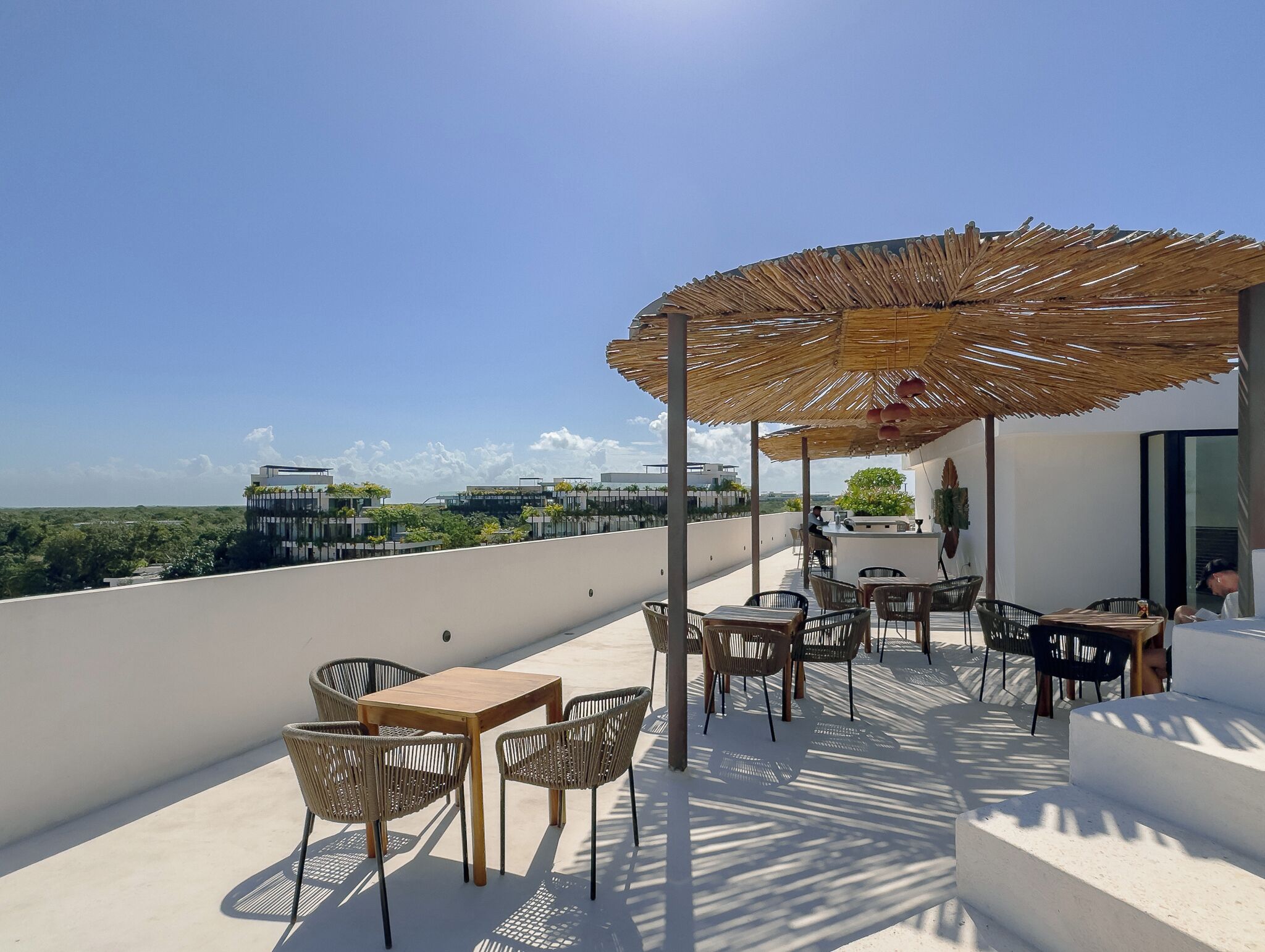 A rooftop terrace with outdoor seating, a bar area, and a view of the cityscape.