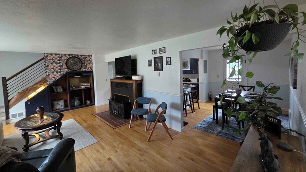 Un salón espacioso con suelo de madera, chimenea, televisión y comedor con mesa y sillas.