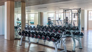 A gym with a mirrored wall, a bench, and a rack of dumbbells.