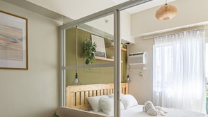 A cozy room with a sofa, a bed, a wooden table, and a hanging plant.