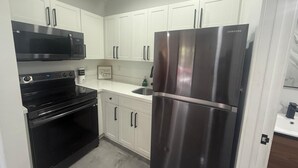 A modern kitchen with white cabinets, a stainless steel refrigerator, a microwave, and an oven. - The Warm Stay  4 (Miami)