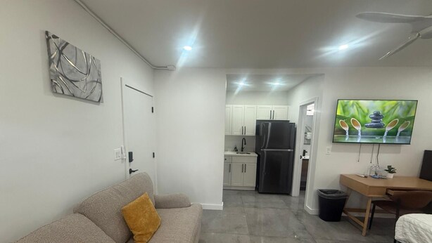A modern living room with a grey sofa, a small coffee table, and a TV mounted on the wall. - The Warm Stay  4 (Miami)