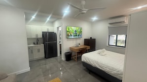A modern, compact room with a bed, desk, and kitchenette. - The Warm Stay  4 (Miami)