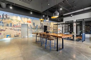 A modern bar area with a mural, bar stools, and pendant lighting. - Designer Apt: Walk to Busch Stadium, Free Parking (St. Louis)