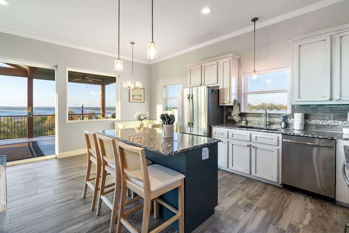 A modern kitchen with a large island, stainless steel appliances, and a view of the outdoors.
