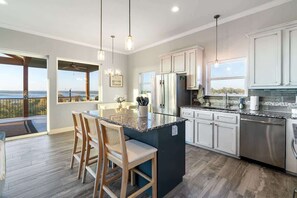 A modern kitchen with a large island, stainless steel appliances, and a view of the outdoors.