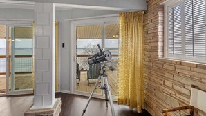 A telescope on a tripod in a room with a view through a glass door. - Panoramic Canyon Lake Views - Retro Star Wars-Inspired Lake House (Canyon Lake)