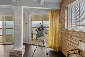 Un telescopio sobre un trípode en una habitación con vista a través de un ventanal.