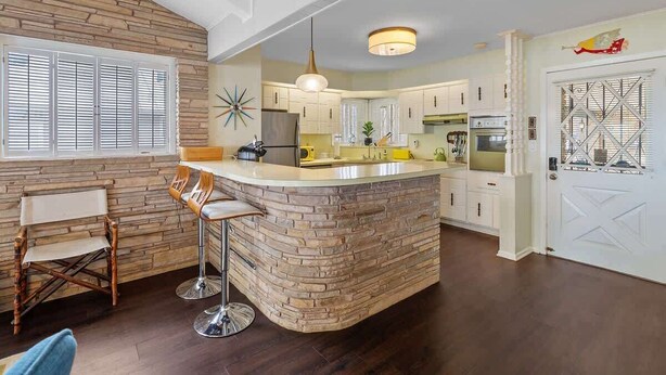 A kitchen with a central island, white cabinets, and a large window with shutters. - Panoramic Canyon Lake Views - Retro Star Wars-Inspired Lake House (Canyon Lake)