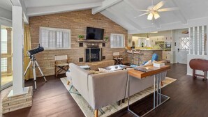 A spacious living area with a fireplace, a television, and a ceiling fan. - Panoramic Canyon Lake Views - Retro Star Wars-Inspired Lake House (Canyon Lake)