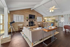 Un salón amplio con chimenea, televisor y ventilador de techo.