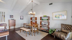 A dining area with a wooden table and chairs, a bench, a chandelier, and a bookshelf with various items. - Panoramic Canyon Lake Views - Retro Star Wars-Inspired Lake House (Canyon Lake)