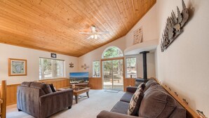 Una sala de estar acogedora con techo de madera, ventanas amplias y chimenea.