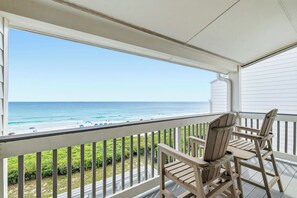 En overdækket balkon med udsigt over stranden og havet.