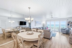 A spacious living area with a large round table, a sofa, and a television. - Beachfront, Decks, Cloud Nine, Sleeps 12, 30A (Inlet Beach)