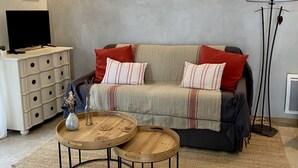 A living room with a sofa, two side tables, a TV, and a lamp.