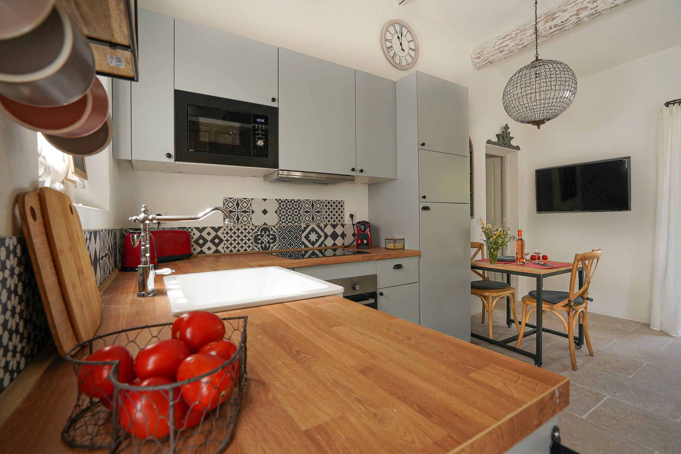 Een moderne keuken met een magnetron, spoelbak en een eethoek met stoelen en een tafel.