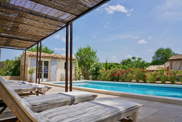 A poolside area with lounge chairs, a swimming pool, and a covered patio.