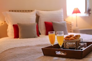 Ein Bett mit Kissen, ein Tablett mit Getränken und Gebäck sowie eine Lampe im Hintergrund.