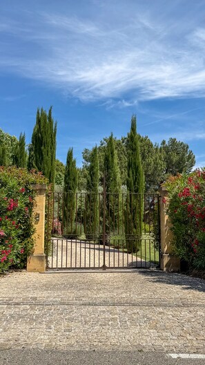 A gated entrance with a gravel driveway leading to a building.