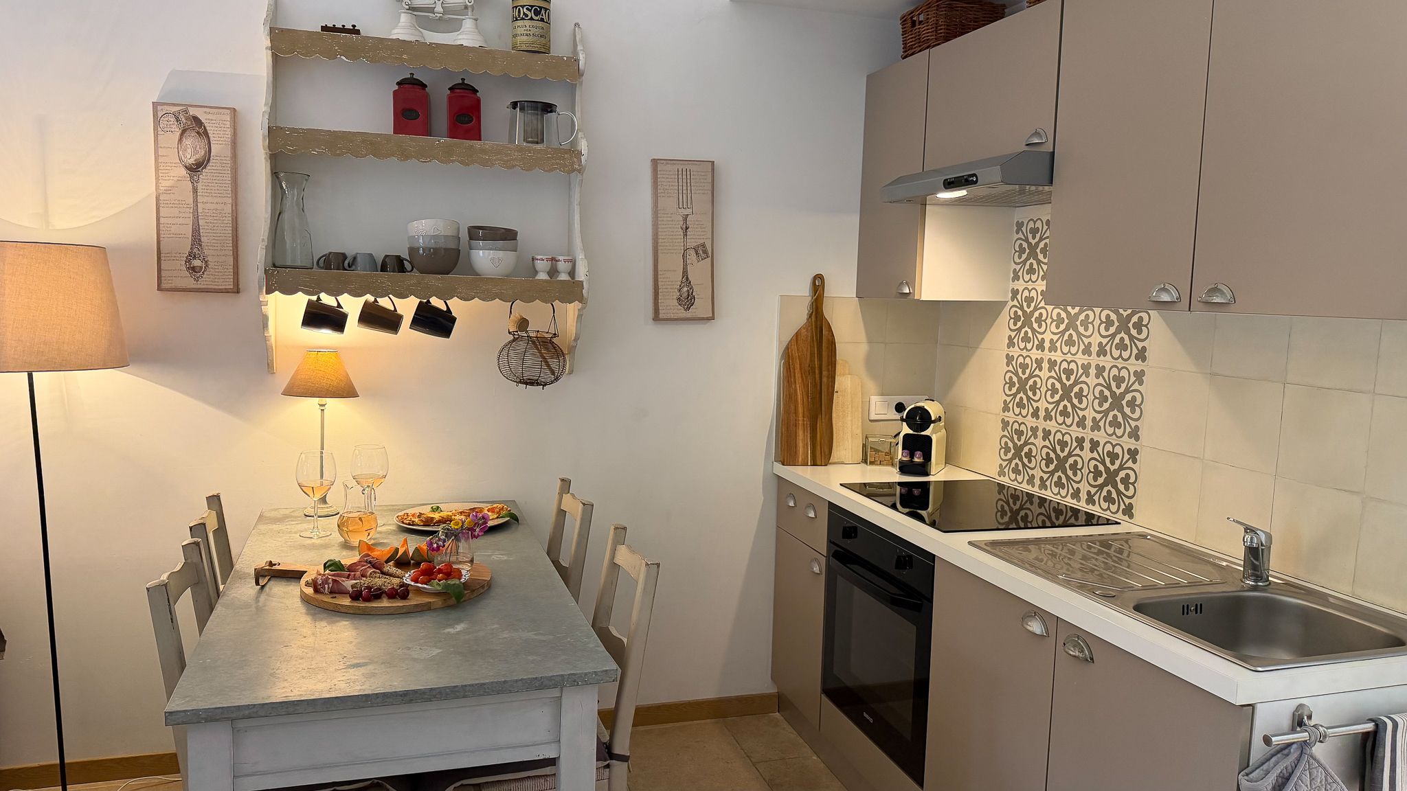 Een keuken met een eettafel gedekt voor twee personen, een spoelbak en een fornuis.